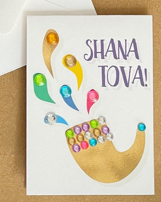 this is a mini note card on a craft paper gift bag with a white envelope and a black marker , the card says Shana Tova in English with a shofar