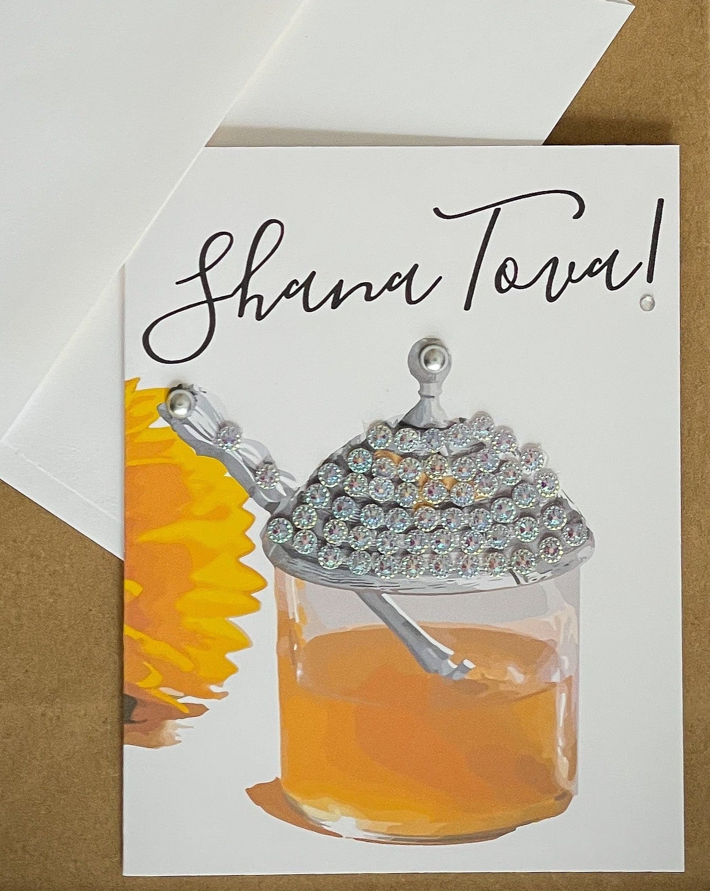 this is a note card on a craft paper gift bag with a white envelope and a black marker , the card says Shana Tova with a a jar of honey